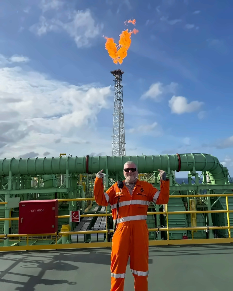 Worker on an offshore platform beside a flare stack